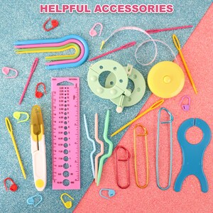 May include: A collection of colourful crochet accessories, including a ruler, stitch markers, a yarn needle, a crochet hook, and a yarn bowl. The accessories are arranged on a blue and pink background.