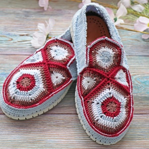 Puede incluir: Un par de zapatillas de crochet azules con patrones geométricos rojos, blancos y marrones.