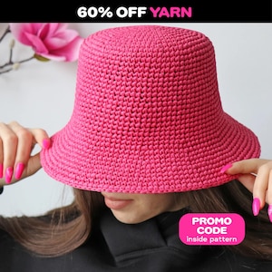 Könnte beinhalten: Ein leuchtend pinkfarbener gehäkelter Fischerhut. Der Hut wird von einer Person gehalten. Das Bild enthält den Text "60% OFF YARN" oben und ein rosa Rechteck mit dem Text "PROMO CODE inside pattern".