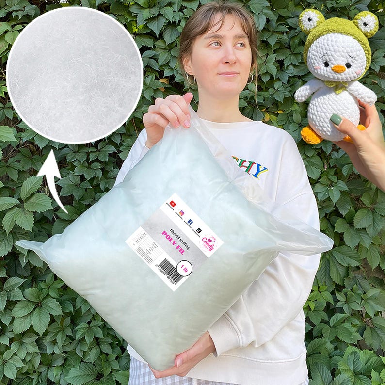 May include: A large clear plastic bag filled with white Poly-Fil fiberfill stuffing, labeled "POLY-FIL" and weighing 1 lb. A close-up shows the fluffy texture. A crocheted duck toy with a green hat is held nearby.