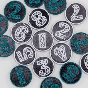May include: A set of 15 black and white round patches with green numbers and intricate designs. The numbers range from 1 to 8.