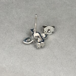 May include: Silver earrings with a heart and a rectangular shape. The earrings are marked with "925" on the back.
