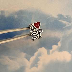 May include: A silver pin with a red heart and the text "I ♥ SP" on a white background.