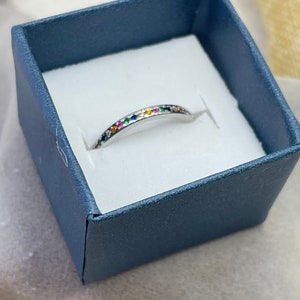 May include: A silver band ring with a row of colorful gemstones set in the band.