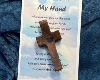 May include: A small wooden cross with a heart carved into it. The cross is on a card with the text "The Cross in My Hand" and a poem about the cross.