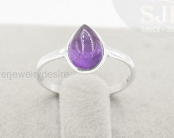 May include: A silver ring featuring a teardrop-shaped, purple amethyst gemstone. The ring has a simple band and a bezel setting that highlights the gemstone. The text "Silverjewelrydesire" is visible.