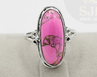 Puede incluir: Un anillo de plata con una piedra ovalada rosa. La piedra tiene un patrón de mármol con motas doradas.