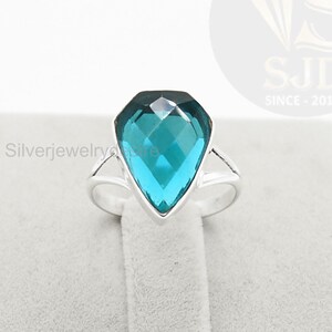 May include: A silver ring with a large, faceted, teal blue gemstone in a teardrop shape.