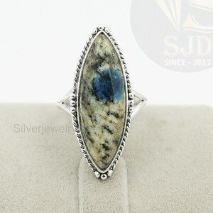May include: A silver ring with a blue and white marbled stone set in a marquise shape. The ring is set in a silver band with a rope-like design.