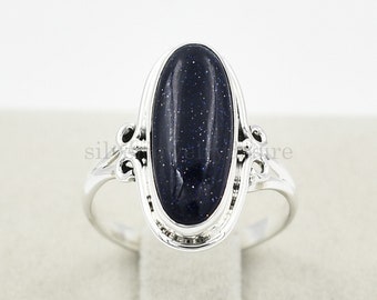 Puede incluir: Un anillo de plata con una piedra ovalada de color azul oscuro. El anillo tiene un diseño delicado y adornado.