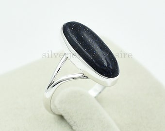 Puede incluir: Un anillo de plata con una piedra ovalada de color azul oscuro. La piedra tiene una textura moteada.