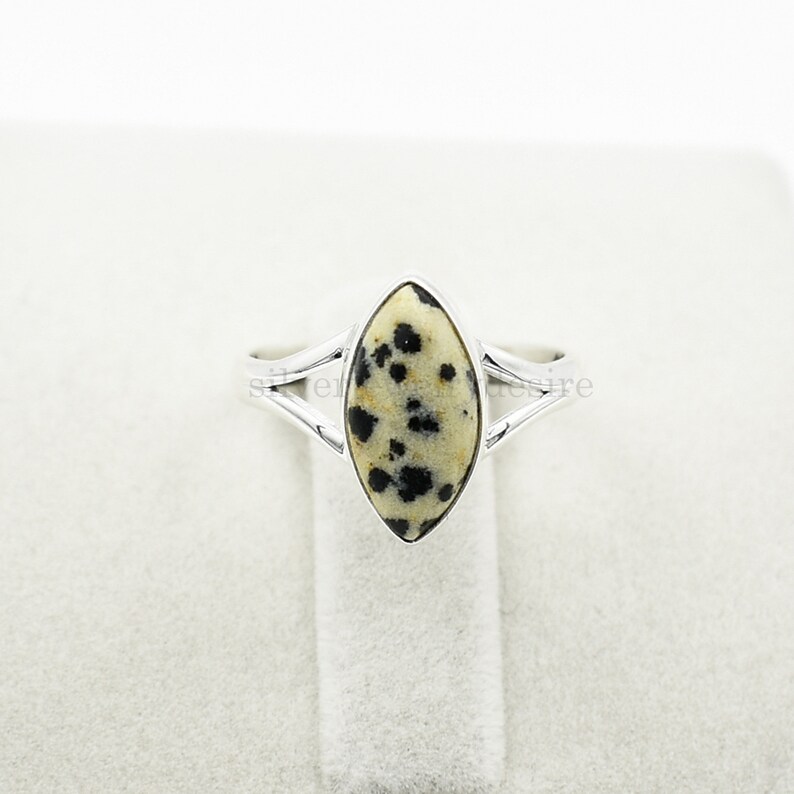 May include: A silver ring with a marbled oval-shaped stone. The stone is white with black spots.