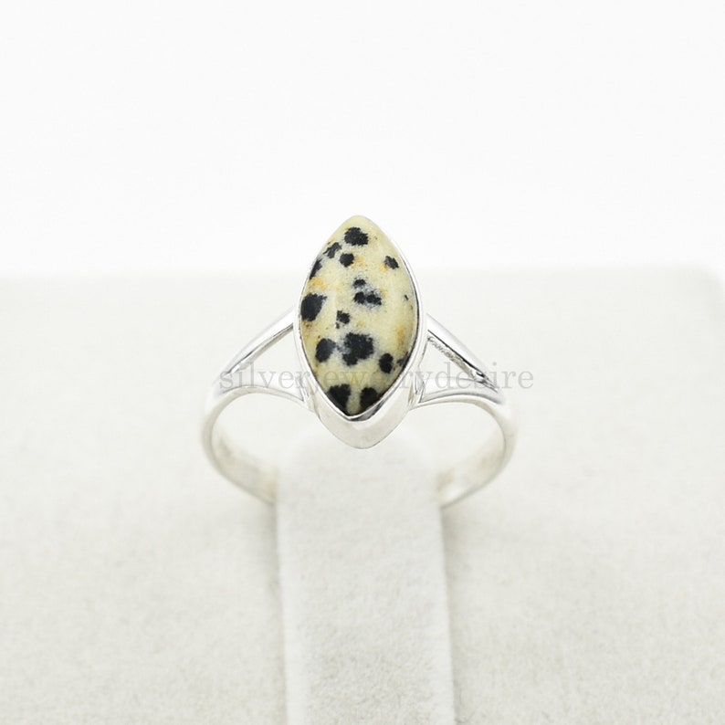 May include: A silver ring with a marbled, black and white gemstone. The gemstone is set in a marquise shape.
