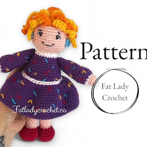 Può includere: Bambola all'uncinetto con capelli arancioni e un vestito viola. La bambola ha un viso sorridente e scarpe rosse. L'immagine include il testo "Pattern" e "Fat Lady Crochet."