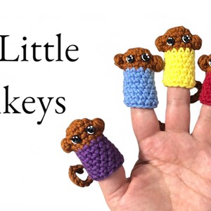 May include: Five little monkeys finger puppets in different colors: purple, blue, yellow, red, and green. The monkeys are brown with black eyes and are wearing crocheted shirts.