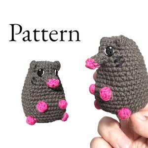 May include: Crochet pattern for a gray and pink mole amigurumi. The pattern includes instructions for making the mole's body, head, nose, and feet.