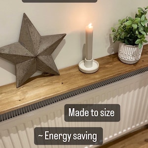 May include: A wooden shelf fitted over a white radiator. The shelf is made to size and is energy saving. The text "Instant impact" and a smiley face with hearts for eyes is at the top of the image. The text "Made to size", "~ Energy saving", and "No drilling" is on the image.