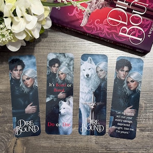 May include: Four rectangular bookmarks featuring illustrations of a couple and a wolf, with text from the book "Dire Bound". The bookmarks have a dark, romantic theme with quotes and the book title.