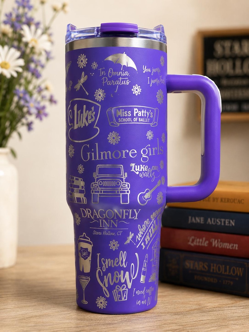 Pu&ograve; includere: Un bicchiere termico viola in acciaio inossidabile con manico, con disegni incisi in argento e testo relativo alla serie TV "Gilmore Girls". Il bicchiere include frasi come "Luke's", "Dragonfly Inn" e "I smell snow".