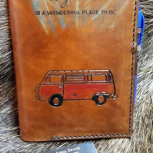 K&ouml;nnte beinhalten: Ein braunes Lederjournal mit den Worten "Together is a wonderful place to be" gepr&auml;gt auf der Vorderseite. Ein roter und wei&szlig;er Vintage-Van ist ebenfalls auf der Vorderseite gepr&auml;gt. Eine Visitenkarte f&uuml;r "JS Original Leather" befindet sich im Vordergrund.