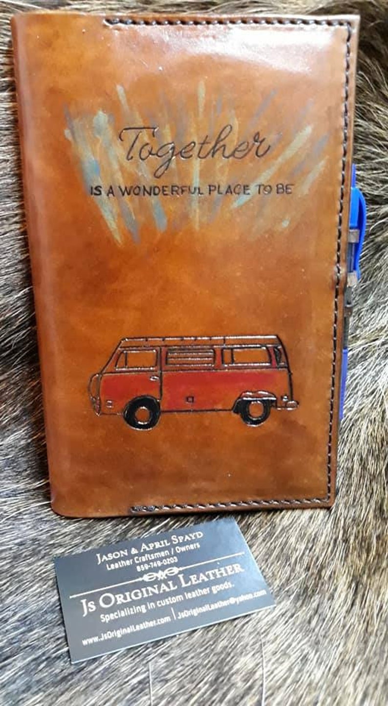 K&ouml;nnte beinhalten: Ein braunes Lederjournal mit den Worten "Together is a wonderful place to be" gepr&auml;gt auf der Vorderseite. Ein roter und wei&szlig;er Vintage-Van ist ebenfalls auf der Vorderseite gepr&auml;gt. Eine Visitenkarte f&uuml;r "JS Original Leather" befindet sich im Vordergrund.