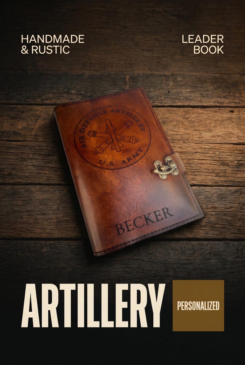 May include: A brown leather journal with the text "Air Defense Artillery U.S. Army" and "Becker" engraved on the cover. The journal has a metal clasp and the words "Handmade & Rustic" and "Leader Book" are also visible.