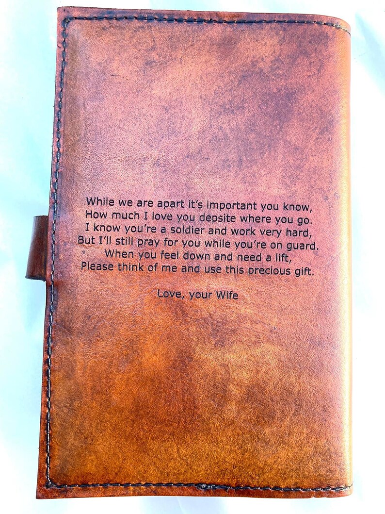 May include: A brown leather journal with a stitched border and a clasp closure. The journal has a heartfelt message engraved on the front, including the words "Love, your Wife."