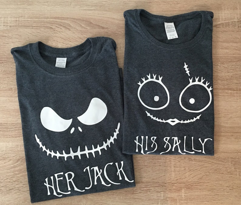 K&ouml;nnte beinhalten: Zwei dunkelgraue T-Shirts mit wei&szlig;en Grafikdesigns. Ein Shirt zeigt ein wei&szlig;es Jack Skellington Gesicht mit dem Text "Her Jack" und das andere Shirt zeigt ein wei&szlig;es Sally Gesicht mit dem Text "His Sally".