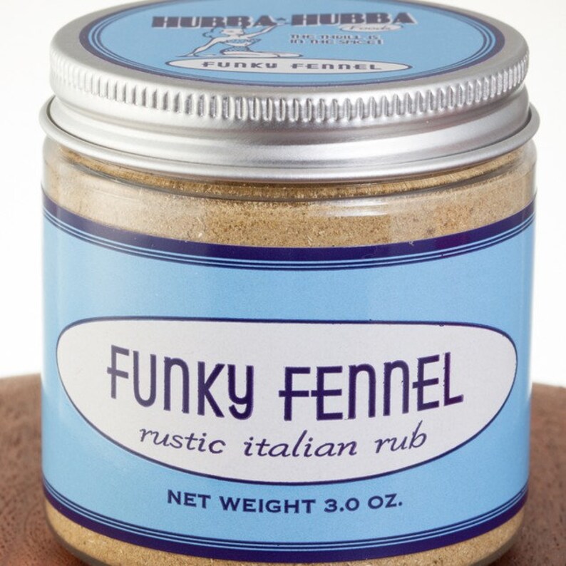 May include: A glass jar with a silver lid filled with a brown spice blend. The label is blue with white text that reads "Funky Fennel rustic italian rub" and "NET WEIGHT 3.0 OZ."