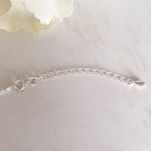 Peut inclure: Une chaînette d'extension de collier argentée dotée d'un fermoir à ressort circulaire à une extrémité et d'une petite breloque métallique lisse en forme de goutte à l'autre. La chaîne se compose de maillons ovales uniformes pour le réglage.
