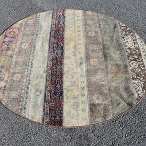 Könnte beinhalten: Ein runder, cremefarbener Teppich mit einem verblassten, mehrfarbigen Muster. Der Teppich hat einen abgenutzten, Vintage-Look und verfügt über einen zentralen Streifen mit einem komplizierteren Design.