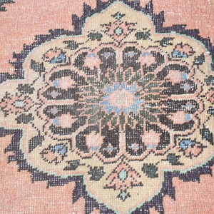 May include: Close-up of a pink rug with a detailed black and white floral design. The rug has a traditional Persian style.