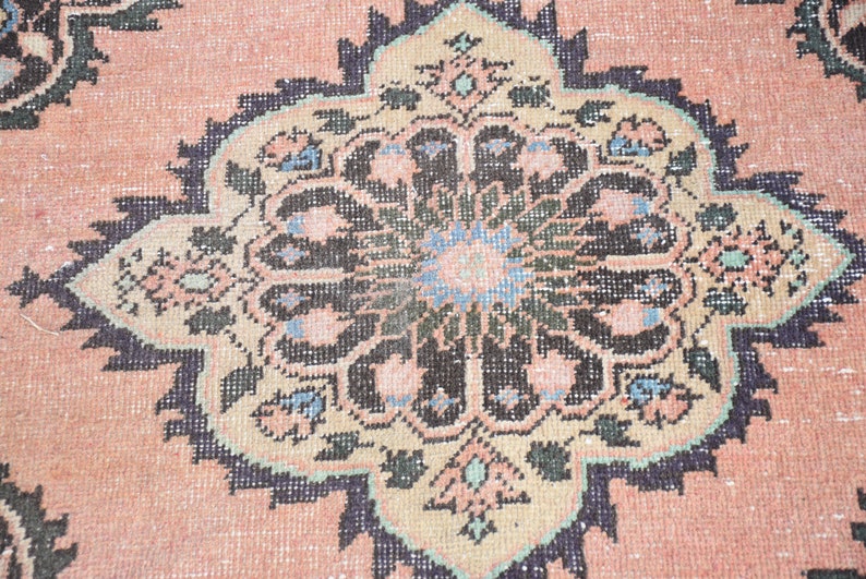 May include: Close-up of a pink rug with a detailed black and white floral design. The rug has a traditional Persian style.