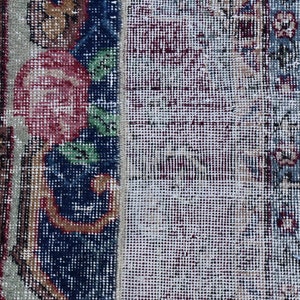 Puede incluir: Primer plano de una alfombra con un patr&oacute;n floral en tonos rojos, azules y verdes. La alfombra tiene un aspecto desgastado y vintage y est&aacute; hecha de un tejido tejido.