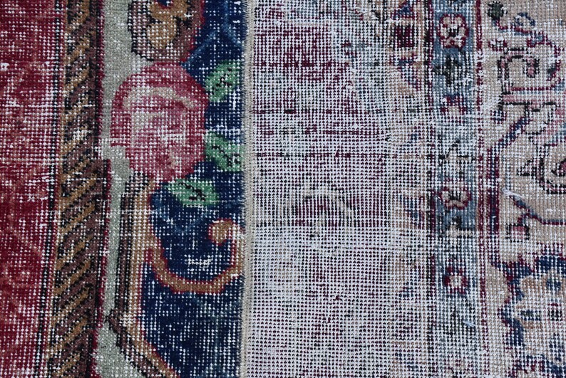 Puede incluir: Primer plano de una alfombra con un patr&oacute;n floral en tonos rojos, azules y verdes. La alfombra tiene un aspecto desgastado y vintage y est&aacute; hecha de un tejido tejido.