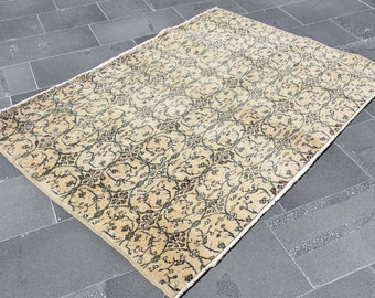 May include: A beige rug with a floral pattern in shades of brown and green. The rug has a fringed edge.