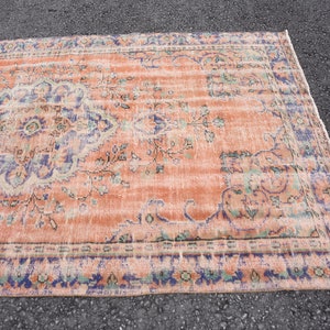 May include: A vintage rug with a peach background and a blue and green floral pattern. The rug has a distressed look and is perfect for adding a touch of bohemian style to your home.
