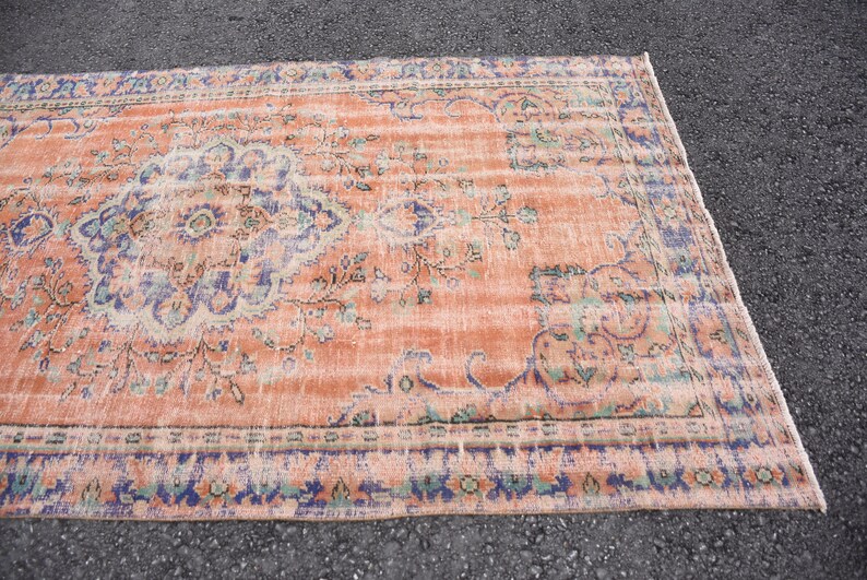 May include: A vintage rug with a peach background and a blue and green floral pattern. The rug has a distressed look and is perfect for adding a touch of bohemian style to your home.
