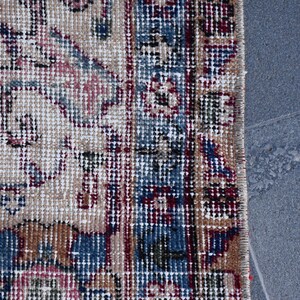 Puede incluir: Primer plano del borde de una alfombra con un patr&oacute;n detallado en tonos de azul, rojo y beige. La alfombra est&aacute; tejida con una textura fina y tiene flecos a lo largo del borde.