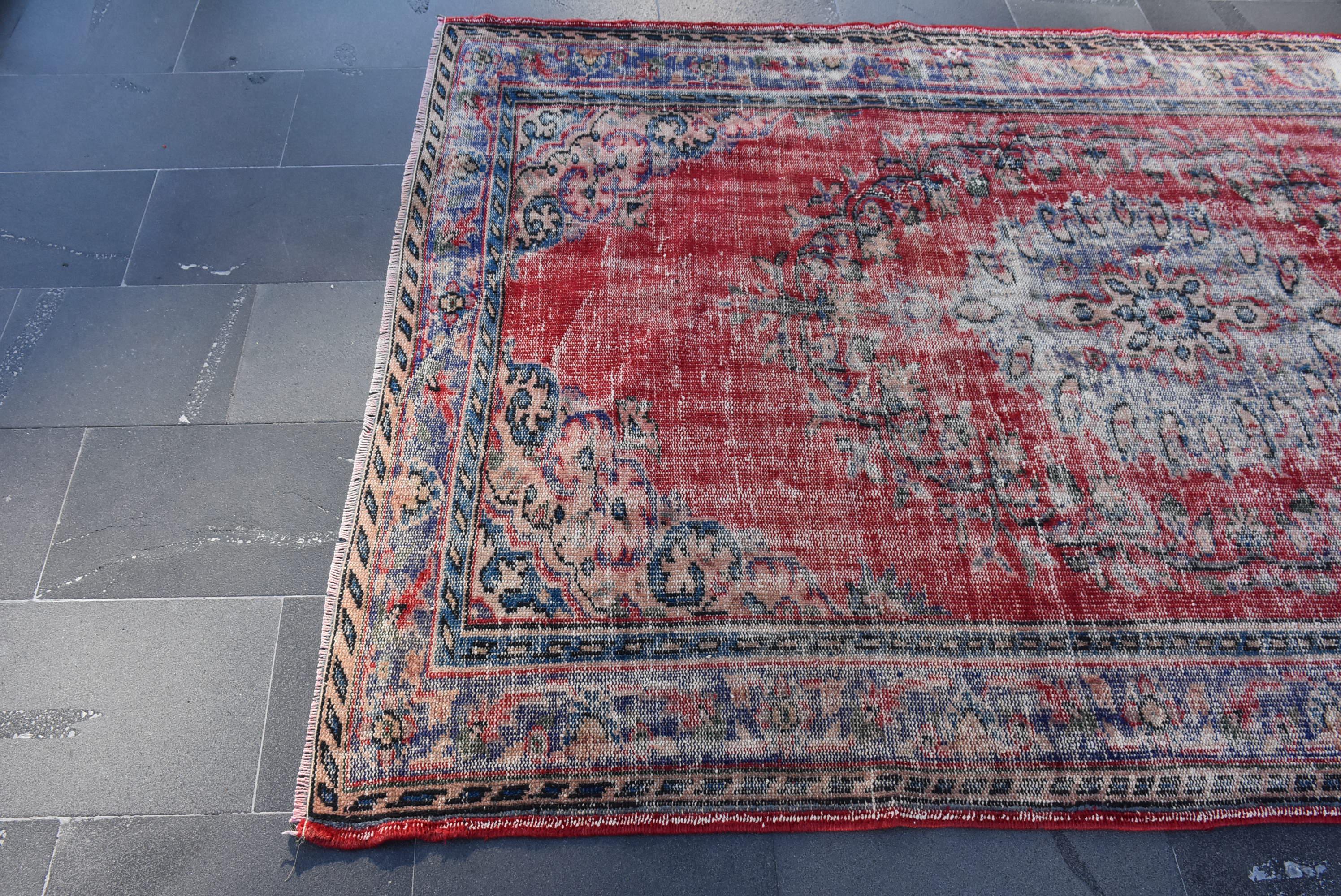 May include: A vintage red and blue rug with a faded floral pattern. The rug has a distressed look and is made of wool.