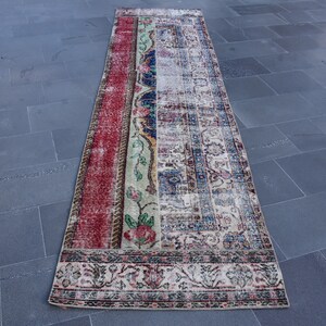 Puede incluir: Una alfombra de pasillo vintage con un dise&ntilde;o de patchwork en rojo, azul, verde y crema. La alfombra tiene un patr&oacute;n floral y un borde con un dise&ntilde;o repetitivo.