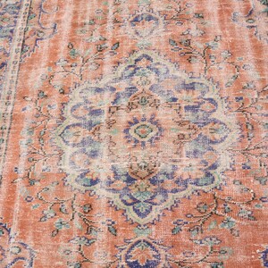 May include: A vintage rug with a faded peach background and a central medallion in shades of blue, green, and cream. The rug has a distressed look with a worn and faded appearance.