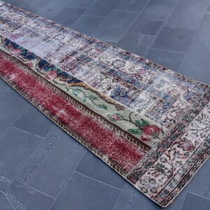Puede incluir: Una alfombra larga y rectangular con un dise&ntilde;o de patchwork. La alfombra tiene un esquema de color rojo, verde, azul y blanco. La alfombra est&aacute; hecha de tejido tejido y tiene un borde con flecos.
