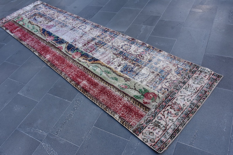 Puede incluir: Una alfombra larga y rectangular con un dise&ntilde;o de patchwork. La alfombra tiene un esquema de color rojo, verde, azul y blanco. La alfombra est&aacute; hecha de tejido tejido y tiene un borde con flecos.
