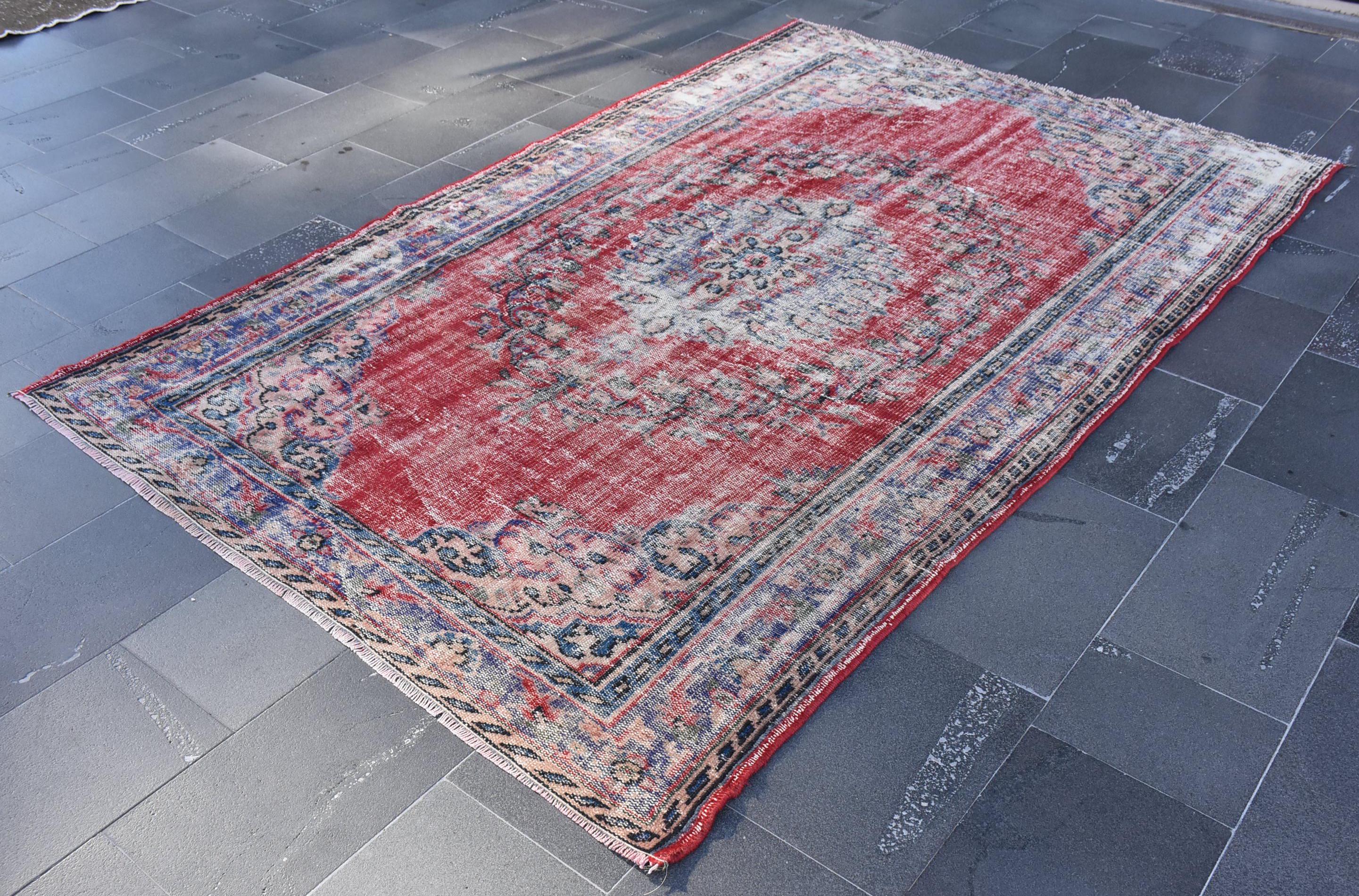 May include: A vintage red and blue rug with a faded floral pattern. The rug has a distressed look and is made of wool.