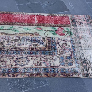 Puede incluir: Una alfombra vintage con un patr&oacute;n floral descolorido en tonos rojos, azules y verdes. La alfombra tiene un aspecto desgastado y est&aacute; hecha de un material suave y tejido.