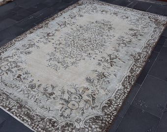 May include: A vintage rug with a floral pattern in shades of brown and white. The rug has a distressed look and a fringed border.