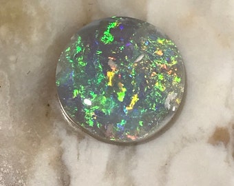 May include: A round, white opal cabochon with green, blue, and gold iridescent flashes.