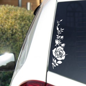 Può includere: Auto bianca con un adesivo di rosa bianca sul lunotto posteriore.
