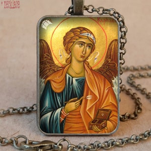 May include: Antique bronze bezel necklace featuring a religious icon of an angel with a gold halo. The rectangular pendant has a detailed image of the angel holding a small box and a tool. The necklace is on a chain.